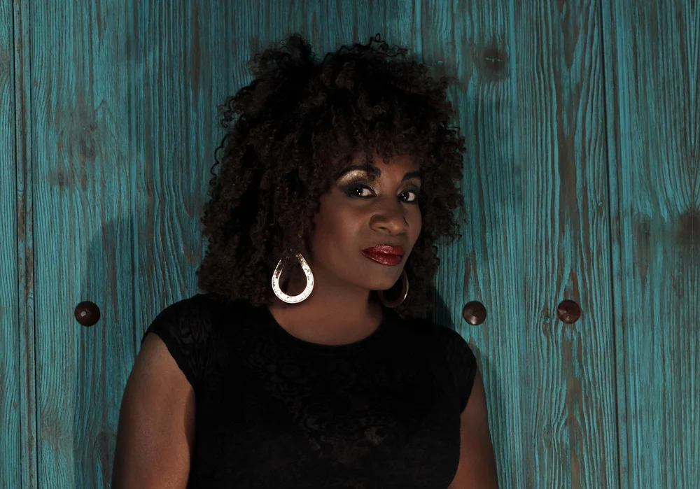 Monalisa Young wearing silver earrings against a teal wooden backdrop